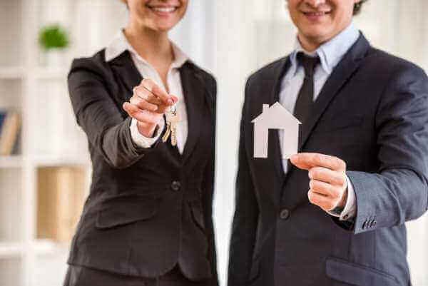 Business people holding model house and keys